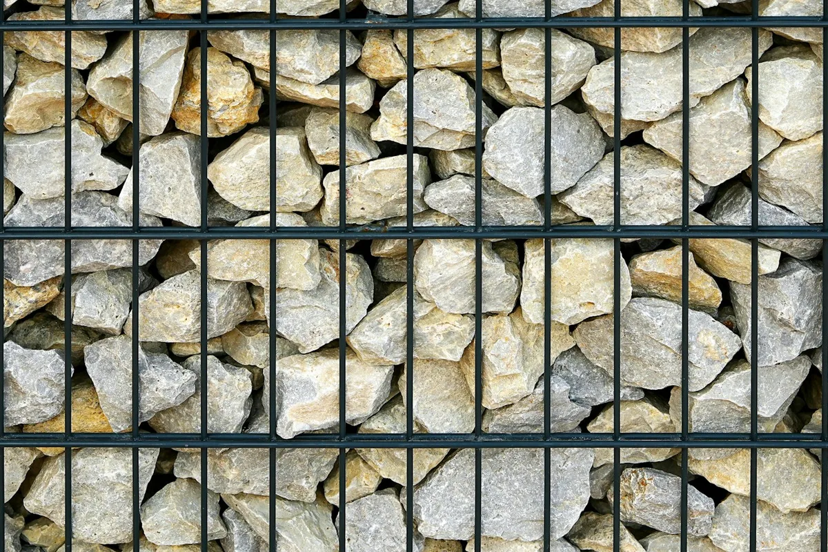 Close view of pale rocks held in a dark steel gabion basket