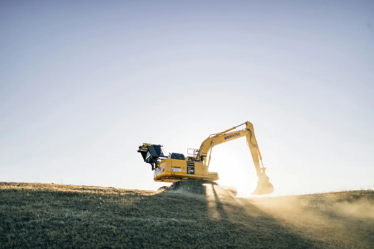 Yellow excavator on an earthworks site beneath a blue sky