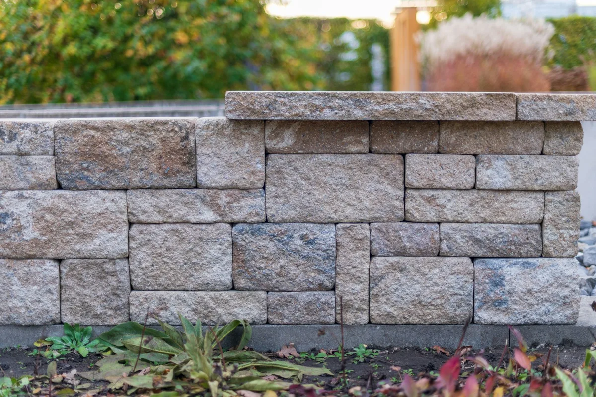 Textured modular masonry garden wall with a stone cap